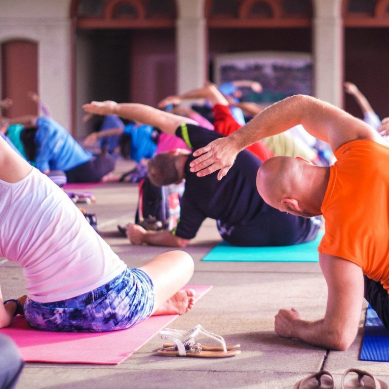 Menschen machen Yoga in einer Gruppe, auf Matten sitzend und sich dehnend.